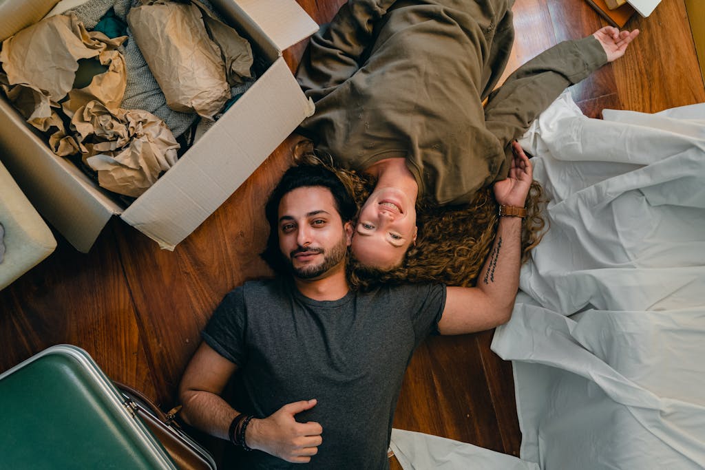 A joyful couple rests on the floor surrounded by moving boxes, symbolizing a fresh start.