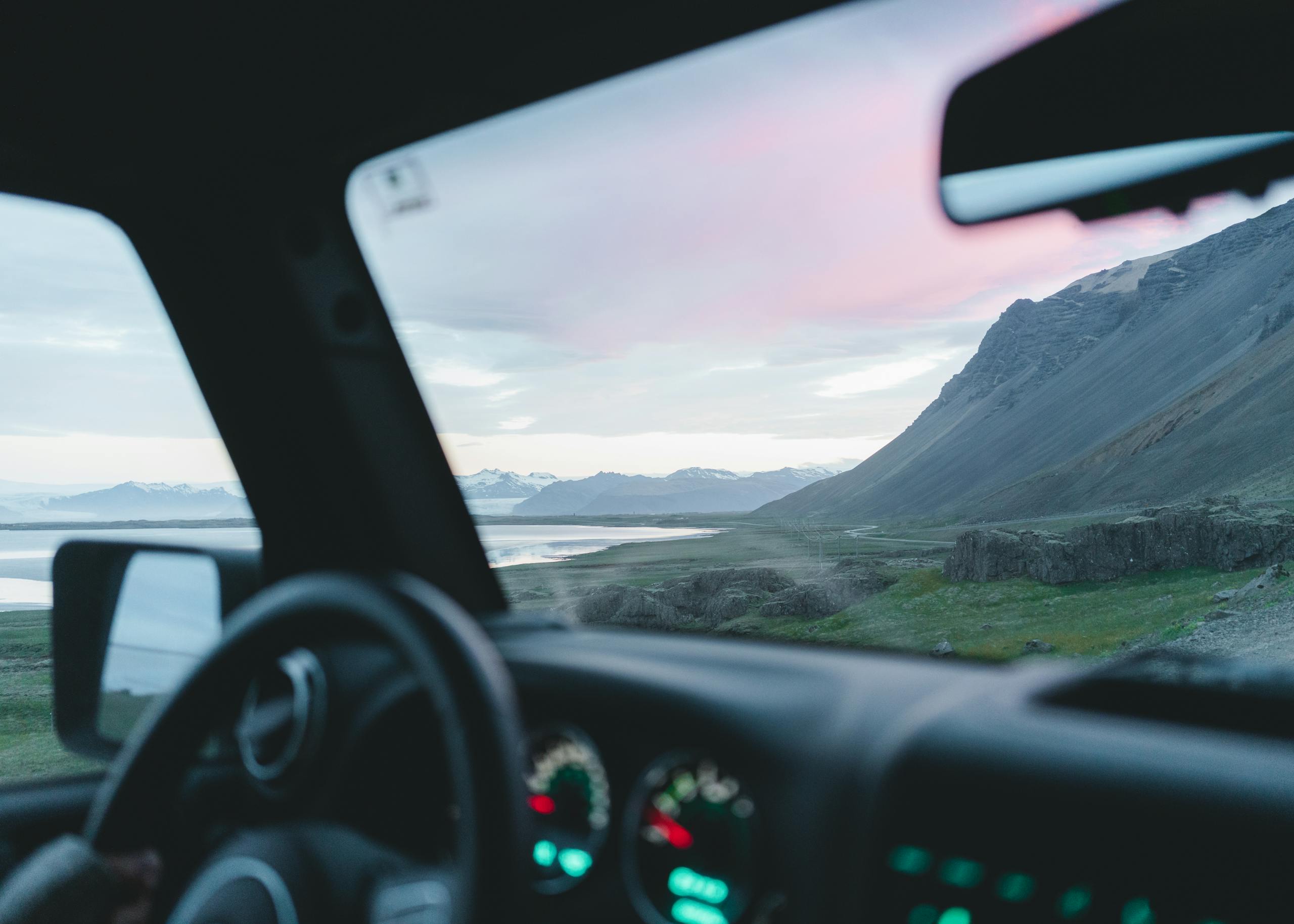 View through car window of Iceland's stunning mountains and rivers during a scenic drive at sunset.