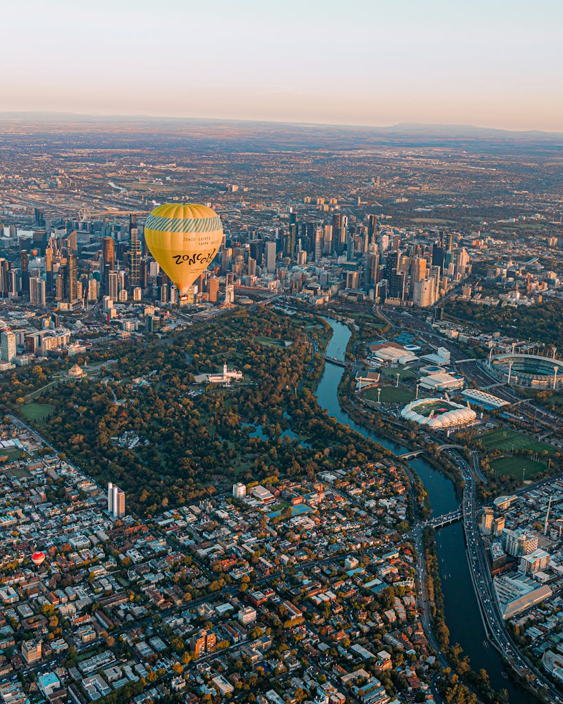 Dramatic aerial shot of a hot air balloon over Melbourne's skyline at sunrise.